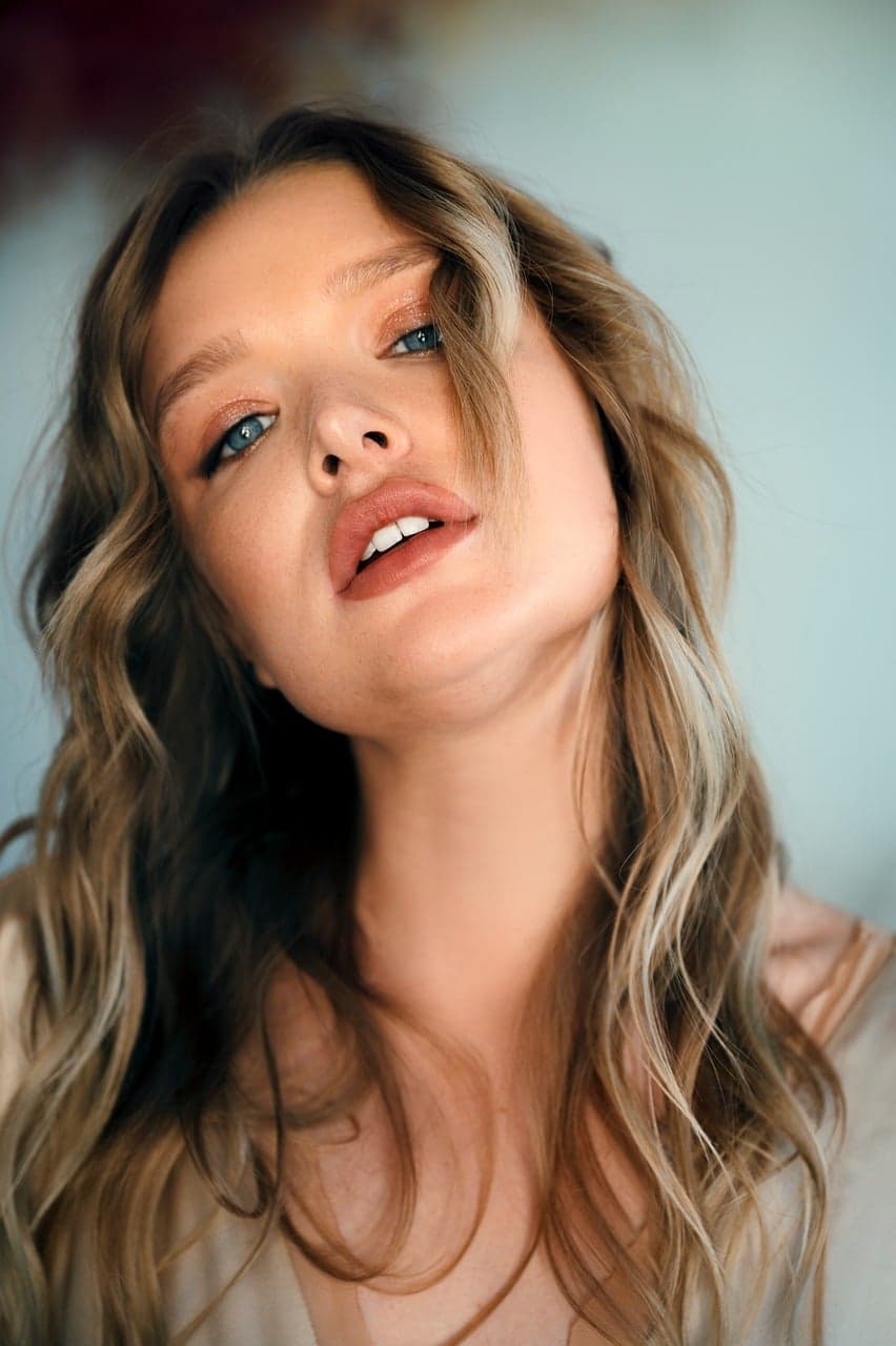 A woman with soft, natural-looking lips, looking up into the light