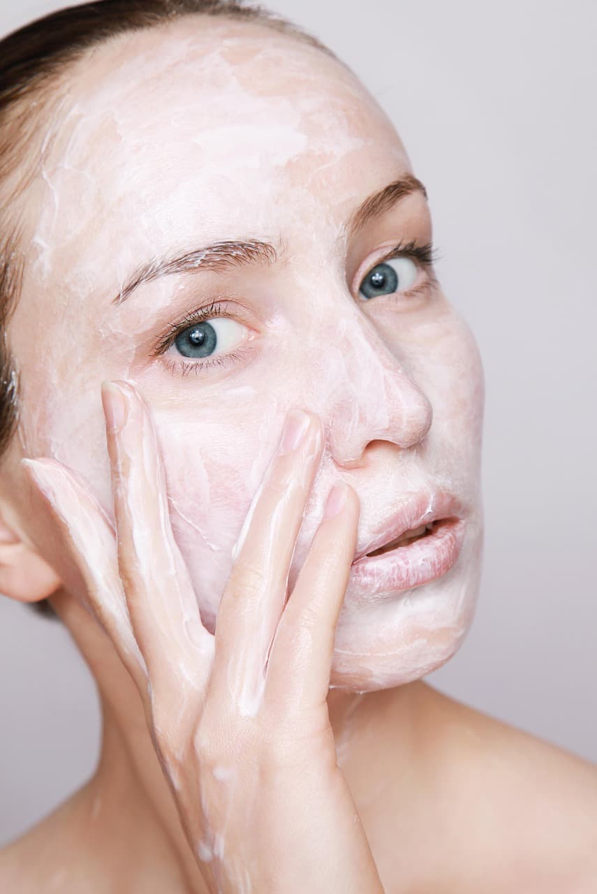 A woman smoothing cream onto her face