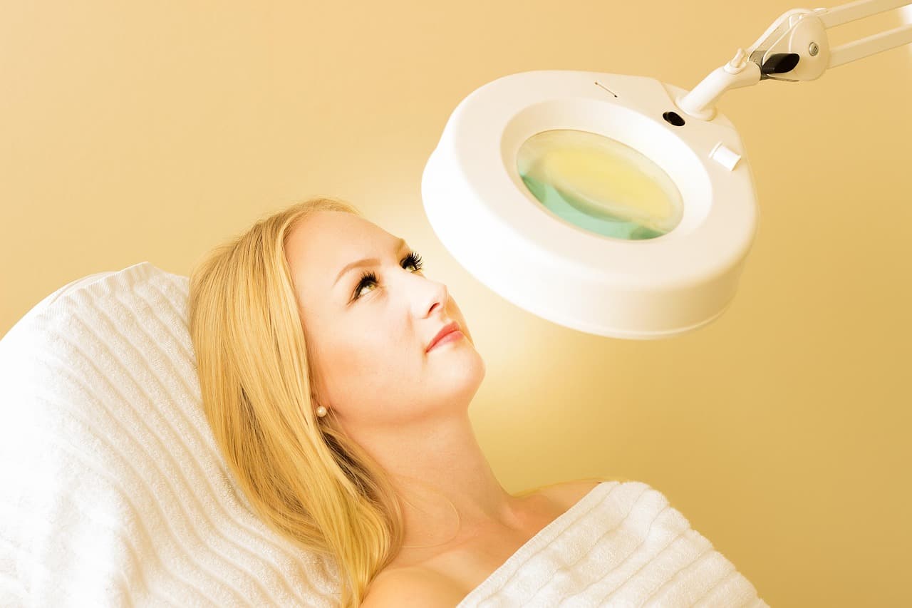 A client under a magnifying lamp before a skin treatment